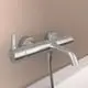 Badearmatur aus Edelstahl von Ideal Standard, montiert an der Wand, mit einem Auslauf und zwei Bedienelementen zur Einstellung der Wassertemperatur und -menge.